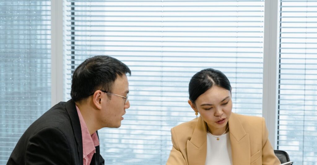 Two business professionals engaged in a meeting with a tablet in a corporate office setting.