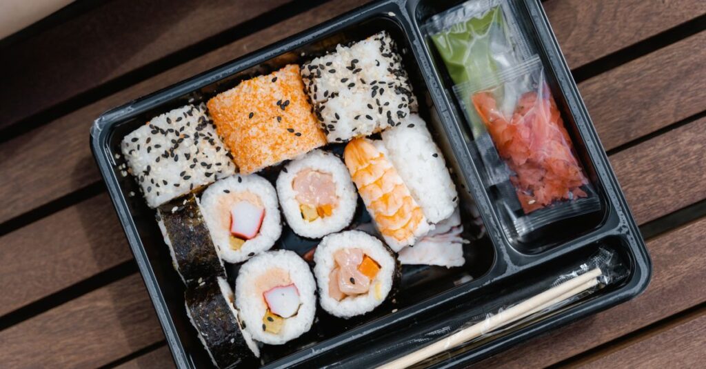 Assorted sushi rolls beautifully arranged in a black bento box, perfect for a quick and tasty meal.