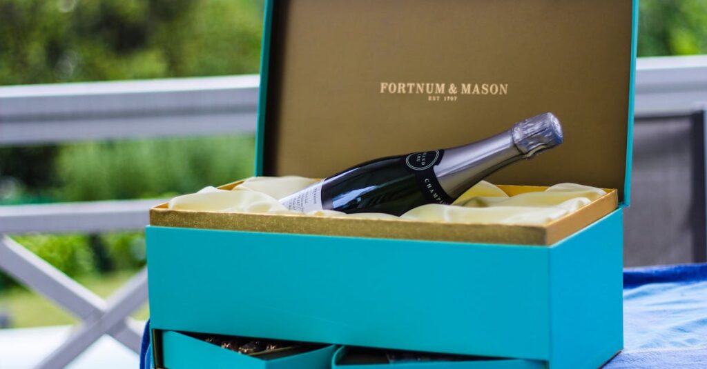 Elegant Fortnum & Mason gift with champagne bottle on table outdoors.