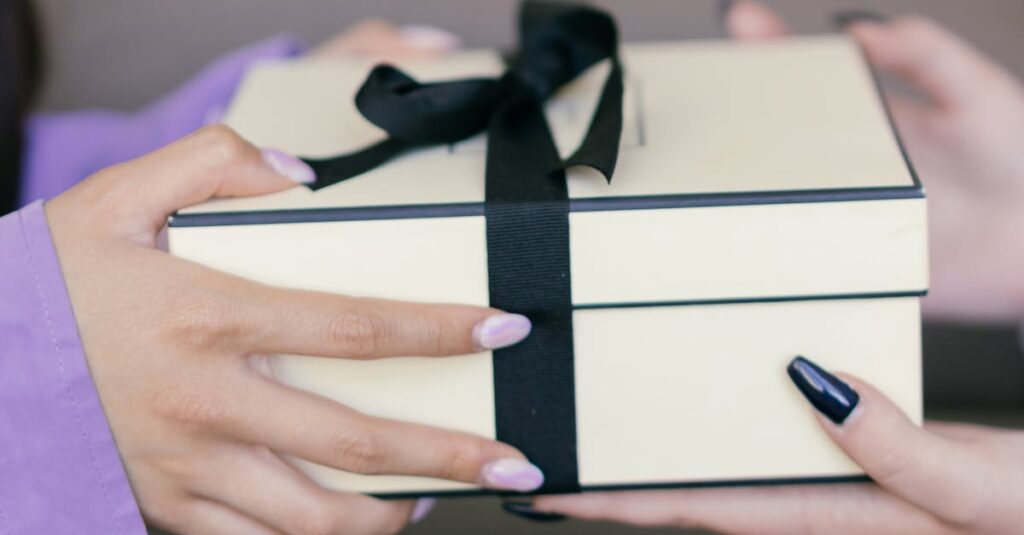 Hands exchanging a decorative gift box with a black ribbon, symbolizing sharing and giving.