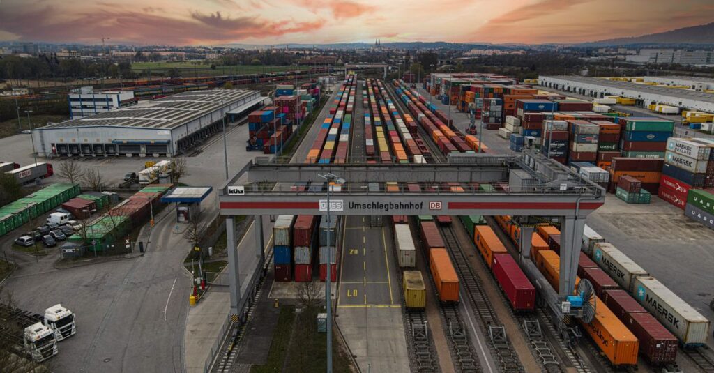 Aerial view of a bustling shipping yard with colorful containers at sunset, highlighting logistics.