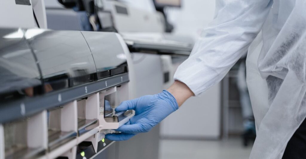 Lab technician in a white coat using equipment with precision in a sterile environment.